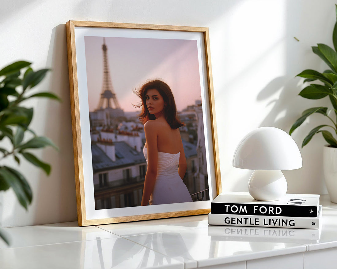 Framed artwork of a woman in Paris with a white lamp and books on a shelf.