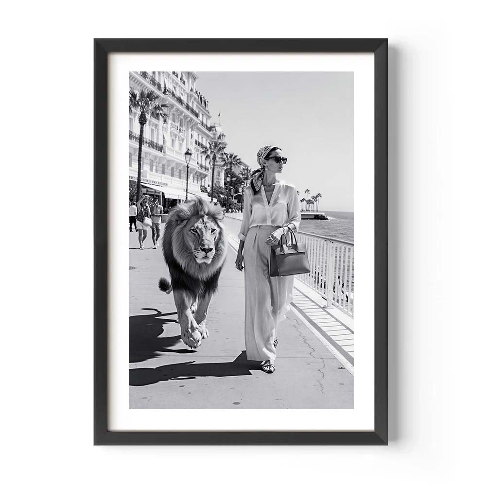 Framed black and white photo of a woman walking a lion on a boardwalk.