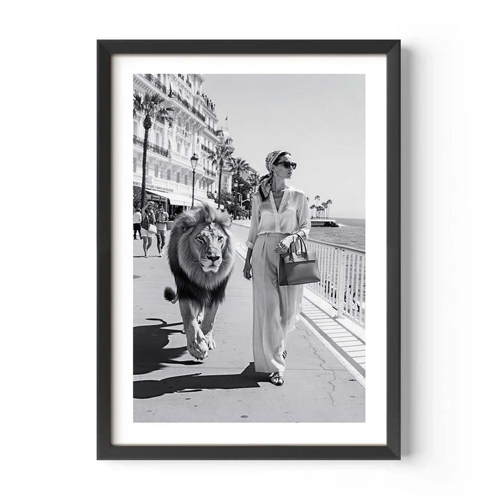 Framed black and white photo of a woman walking a lion on a boardwalk.
