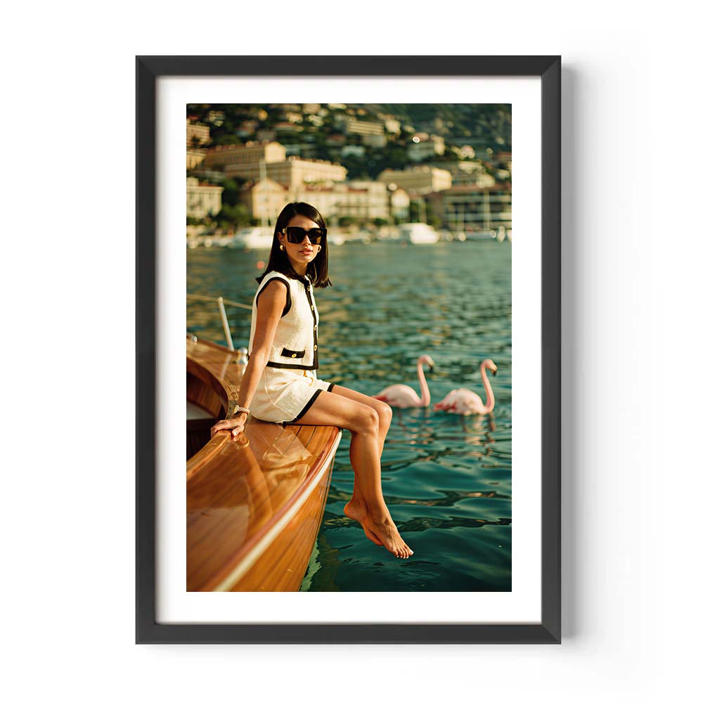 Framed photograph of a woman sitting on a boat with swans in the water.