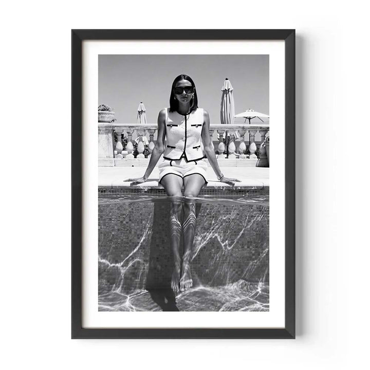 Framed black and white photo of a person sitting by a pool.