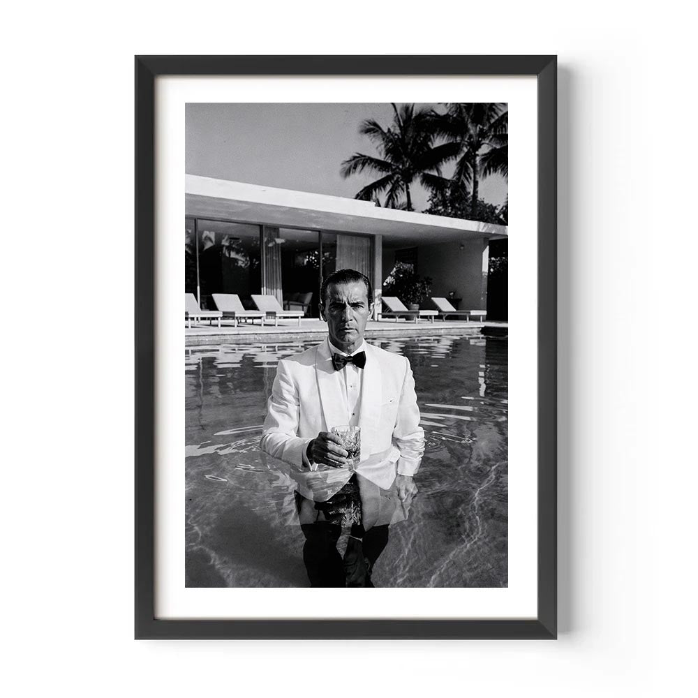 Framed black and white photo of a man in a pool with palm trees in the background