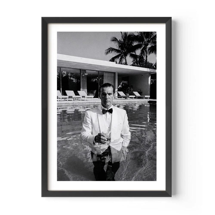 Framed black and white photo of a man in a pool with palm trees in the background