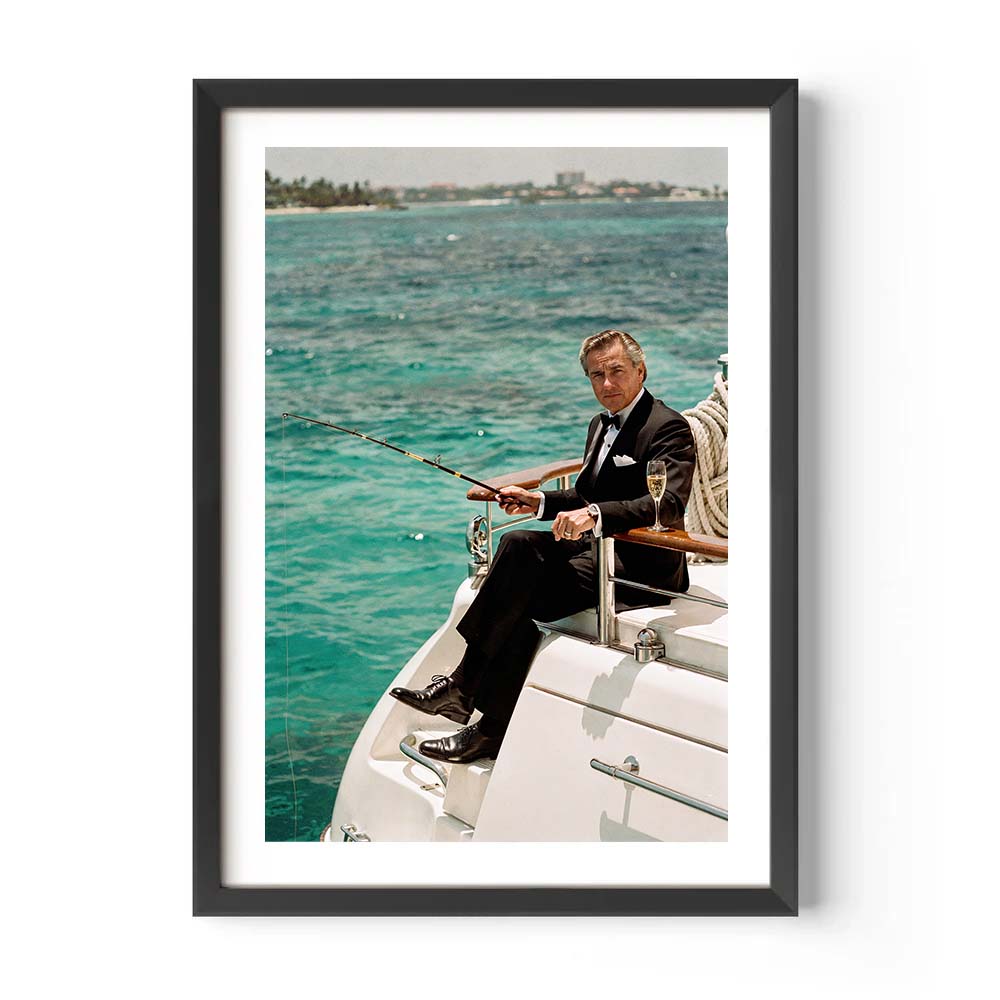 Framed picture of a man in a suit fishing on a boat with turquoise water in the background.