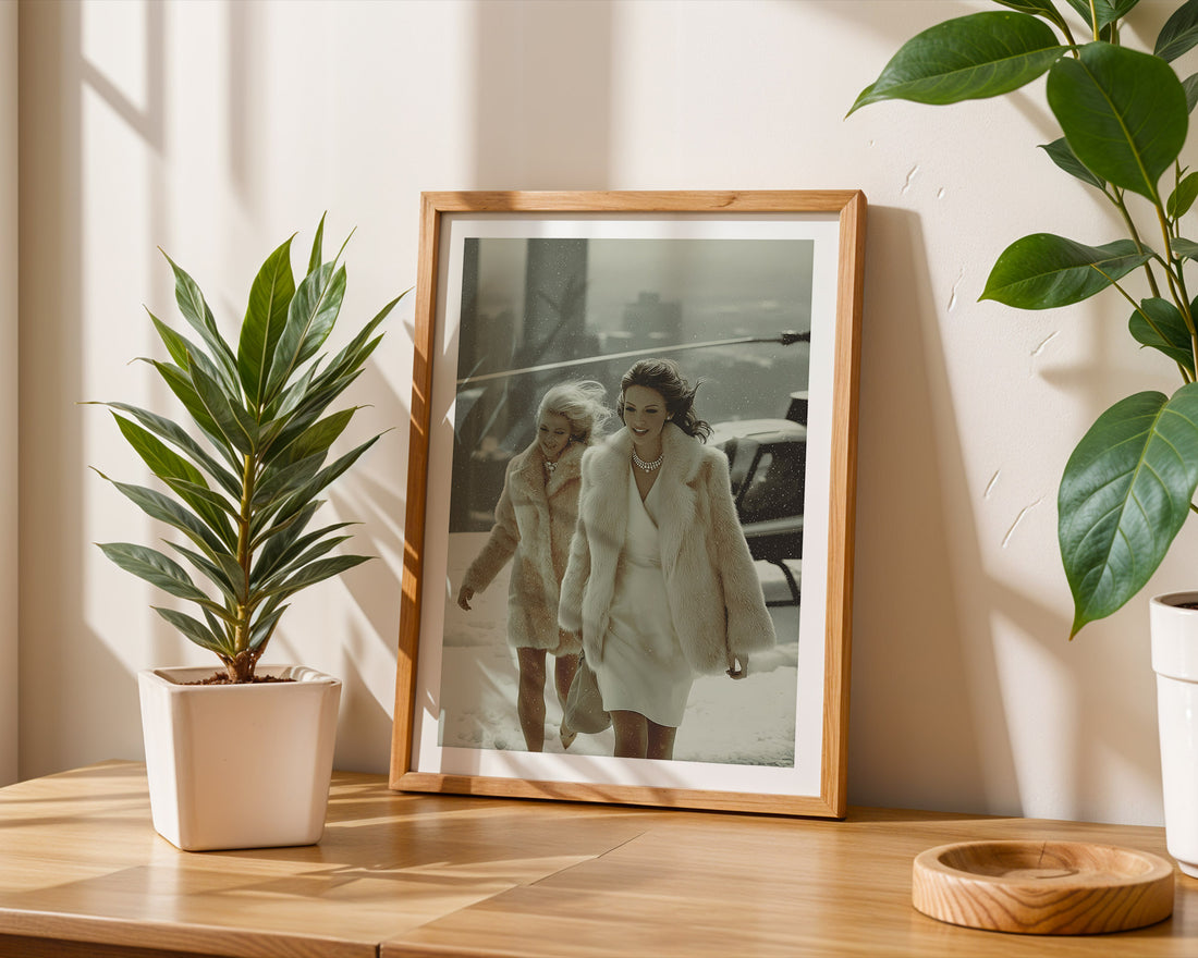Framed photograph of two women in fur coats on a table with plants