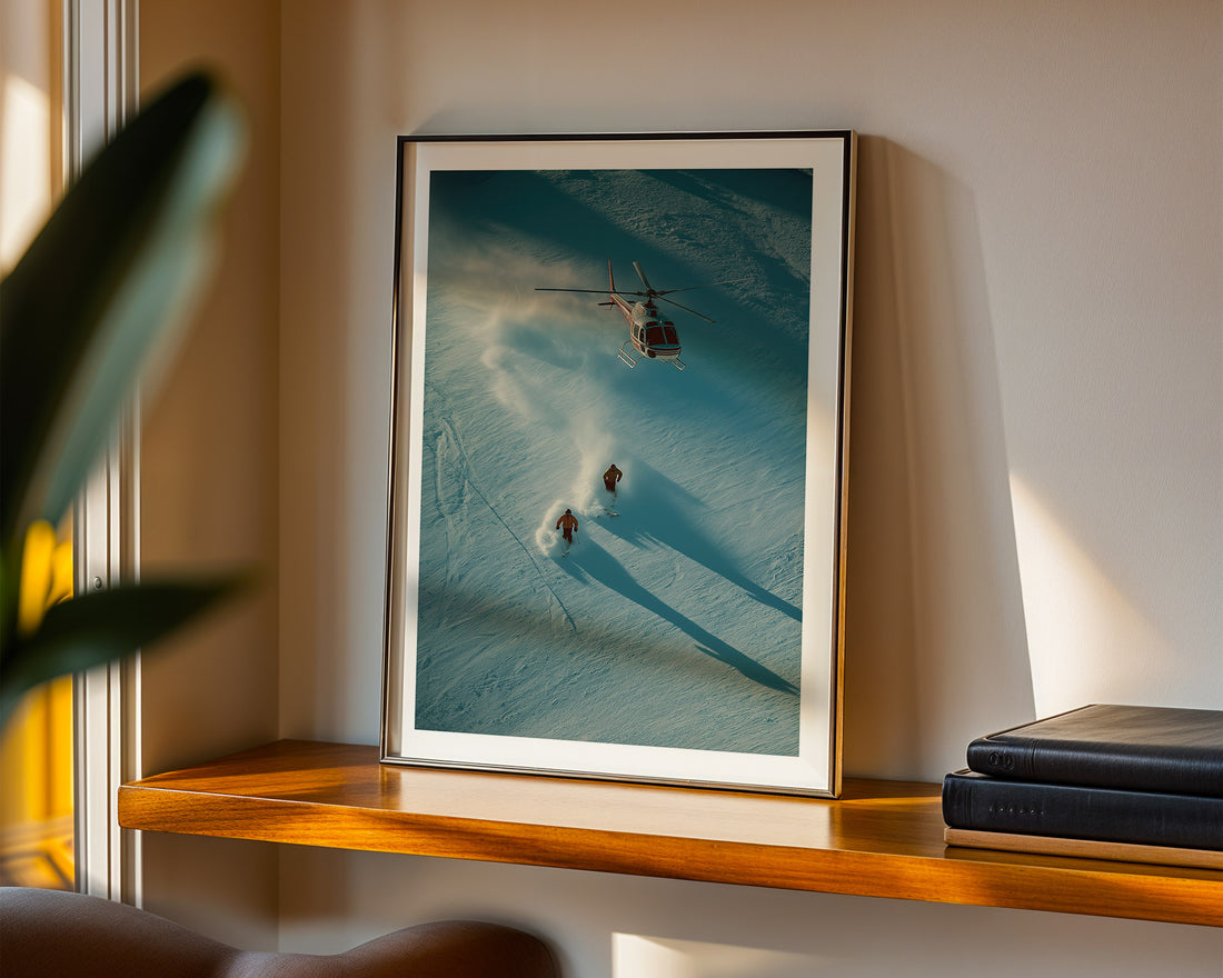 Framed photograph of a helicopter and skiers on a mountain wall-mounted on a shelf.