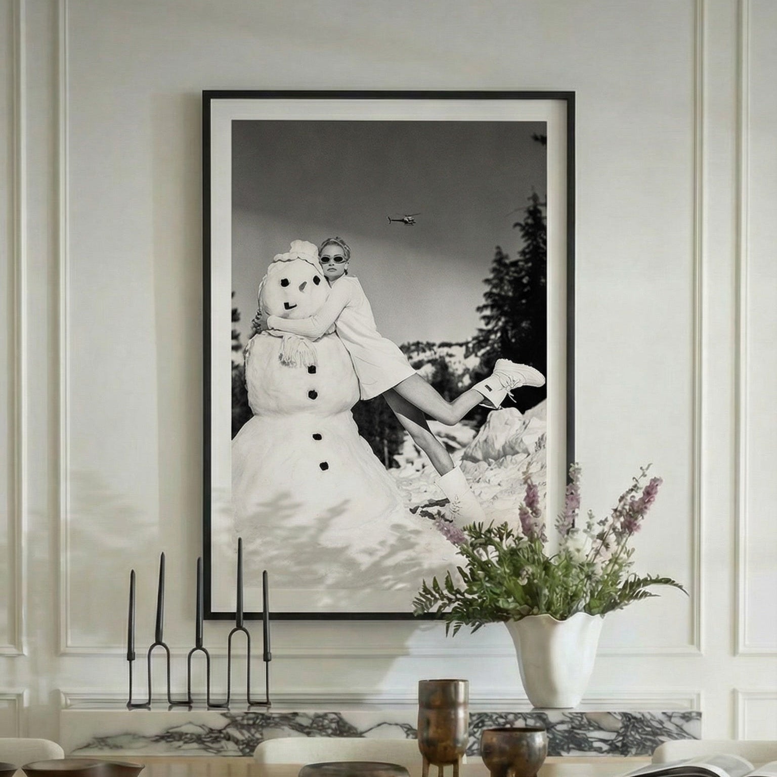 Dining room with a large framed black and white photograph on the wall, floral arrangement, and candles.