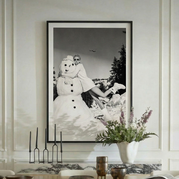 Dining room with a large framed black and white photograph on the wall, floral arrangement, and candles.