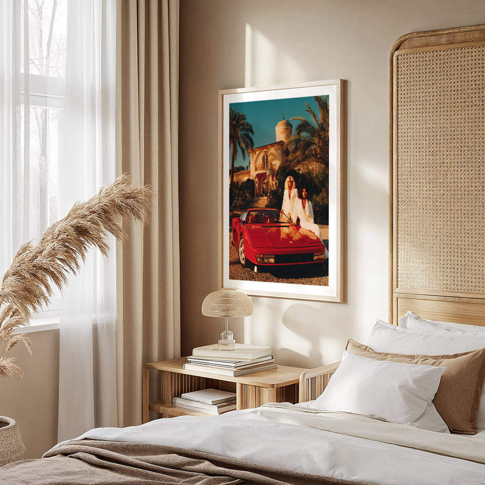Neatly made bed with a red Ferrari and palm tree scene on the wall in a bedroom setting.