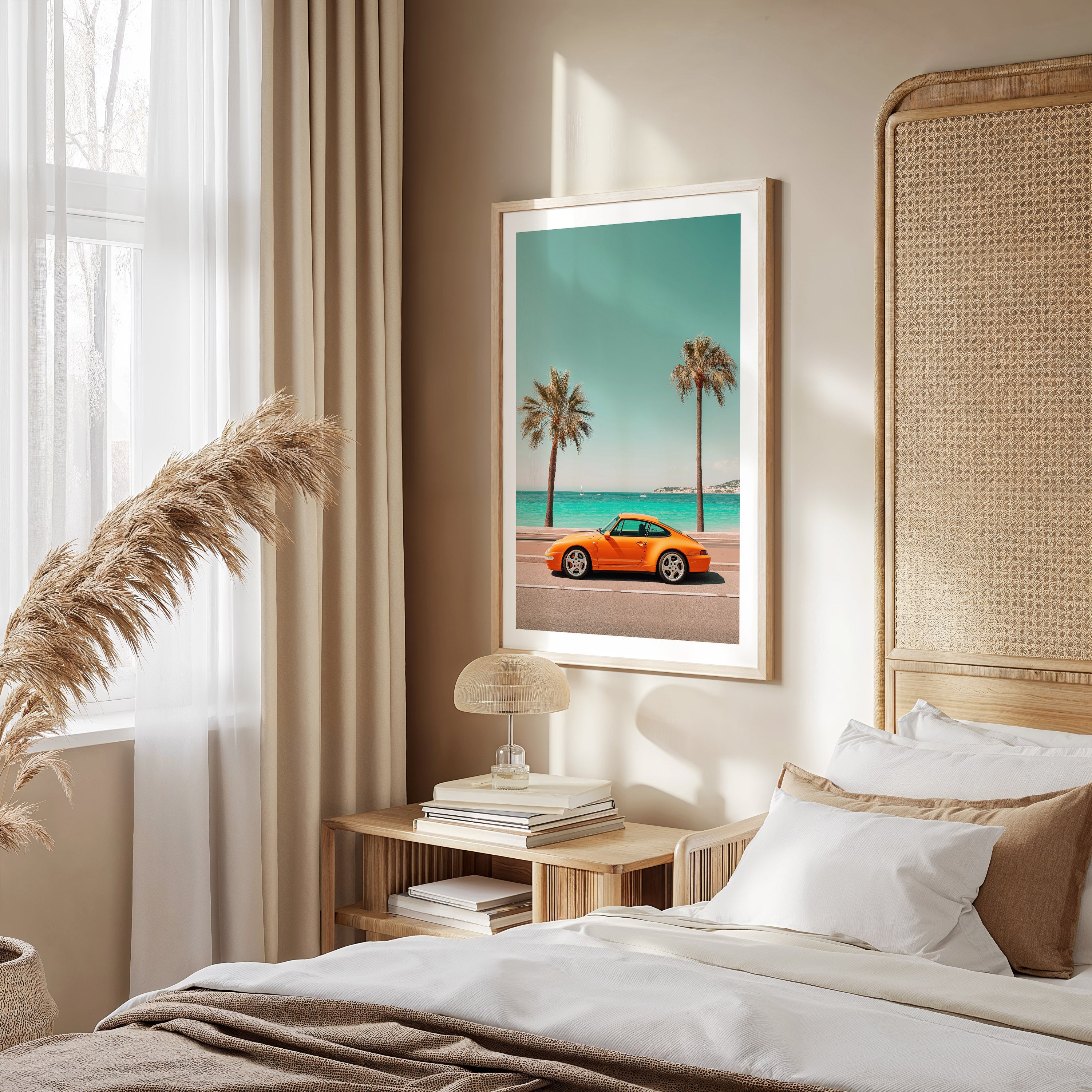 Bedroom with a framed picture of a Porsche on a beach, white curtains, and a wooden nightstand.