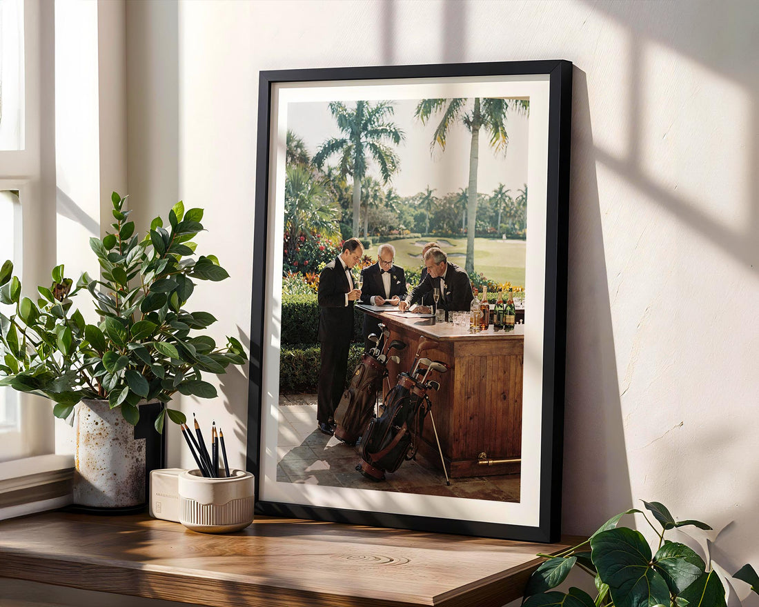 Framed photograph of a golf-themed event on a wooden shelf with plants.