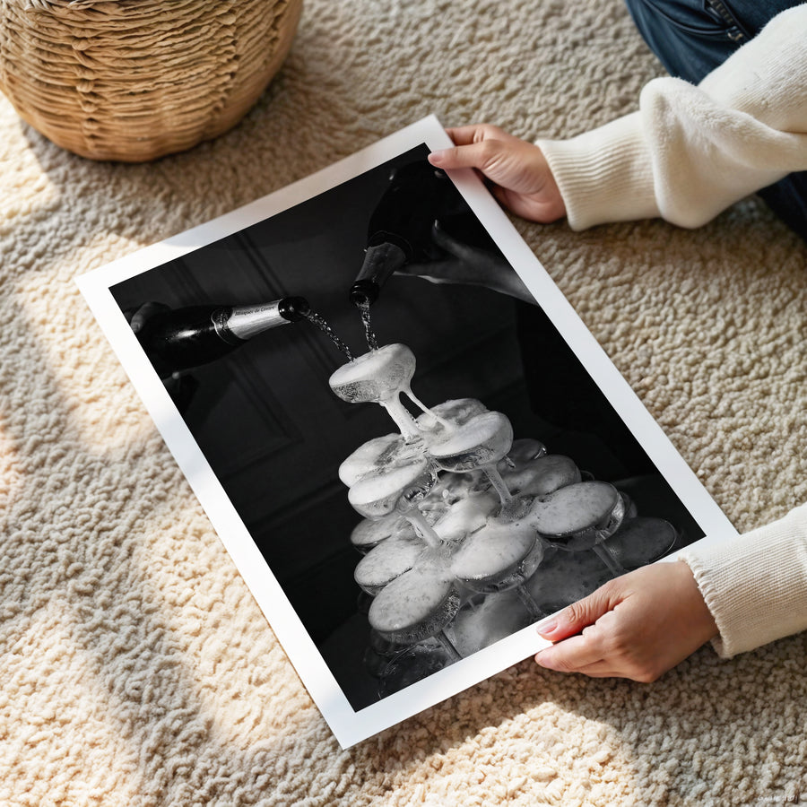 Person holding a black and white photograph of a faucet and water droplets on a carpeted floor.