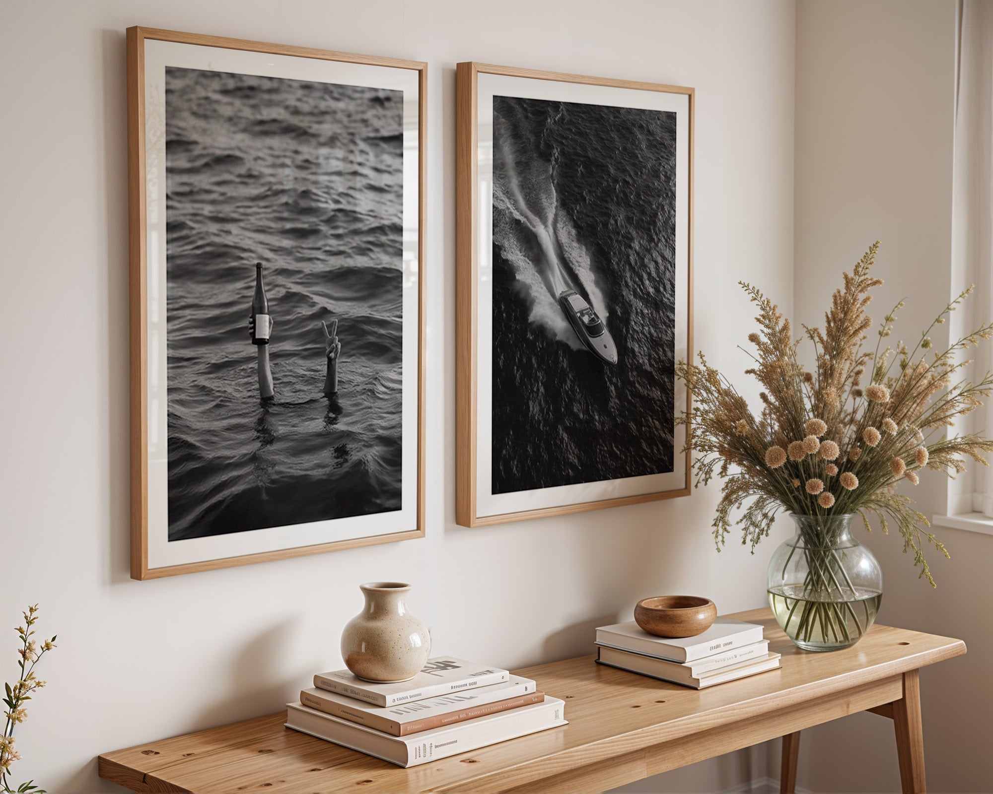 Two framed black and white artworks on a wall above a wooden console table with decorative items.