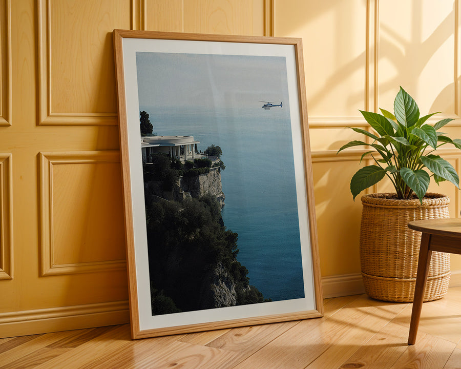 Framed photograph of a scenic view with a helicopter over water, leaning against a wooden wall.