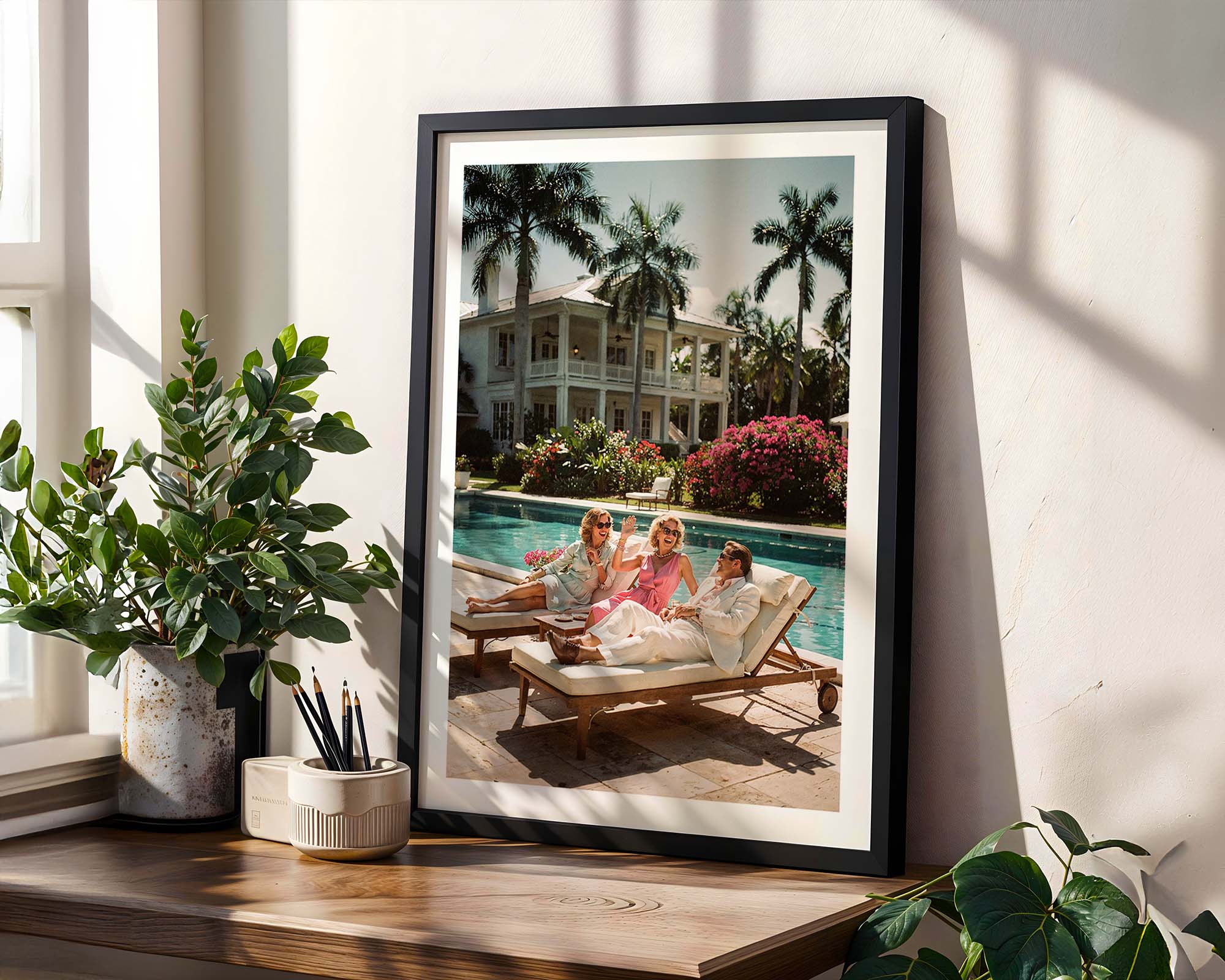 Framed photograph of a family by a pool with decorative plants around.