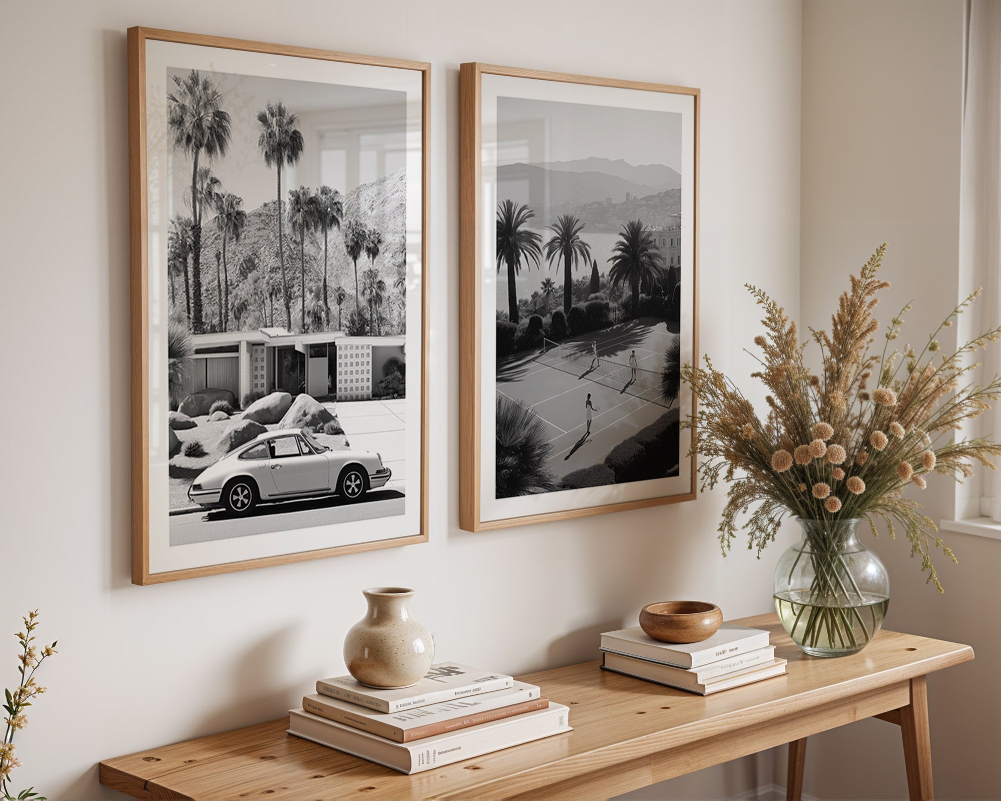 Two framed black and white prints of a city street scene with palm trees, placed above a wooden console table with decorative items.