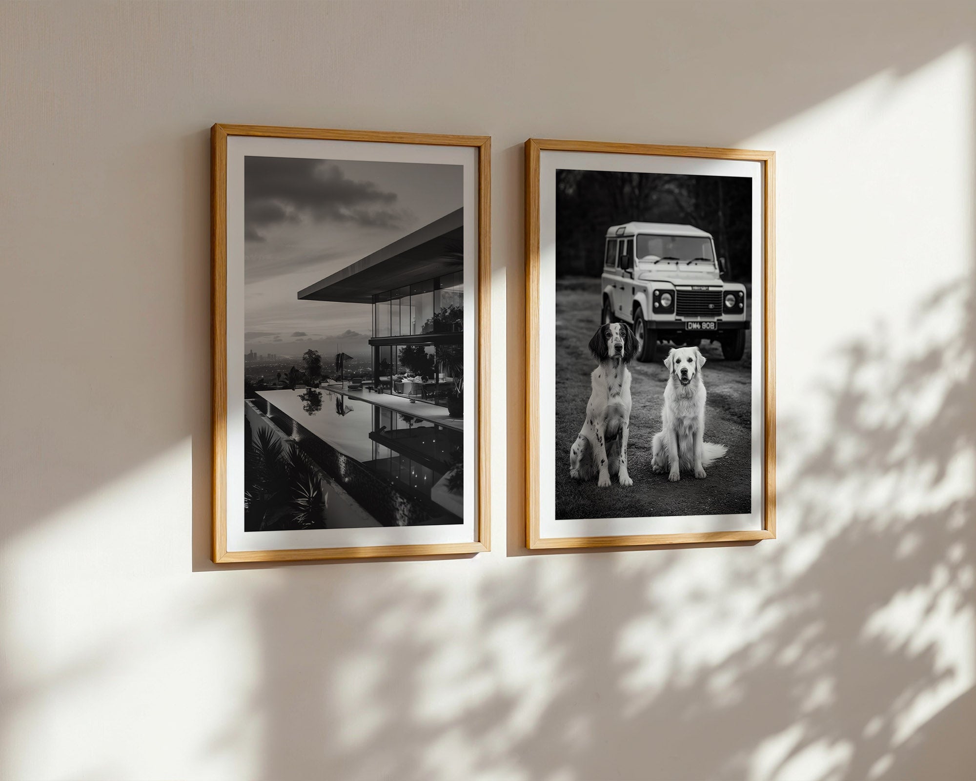Two framed black and white photos on a wall with sunlight casting shadows.