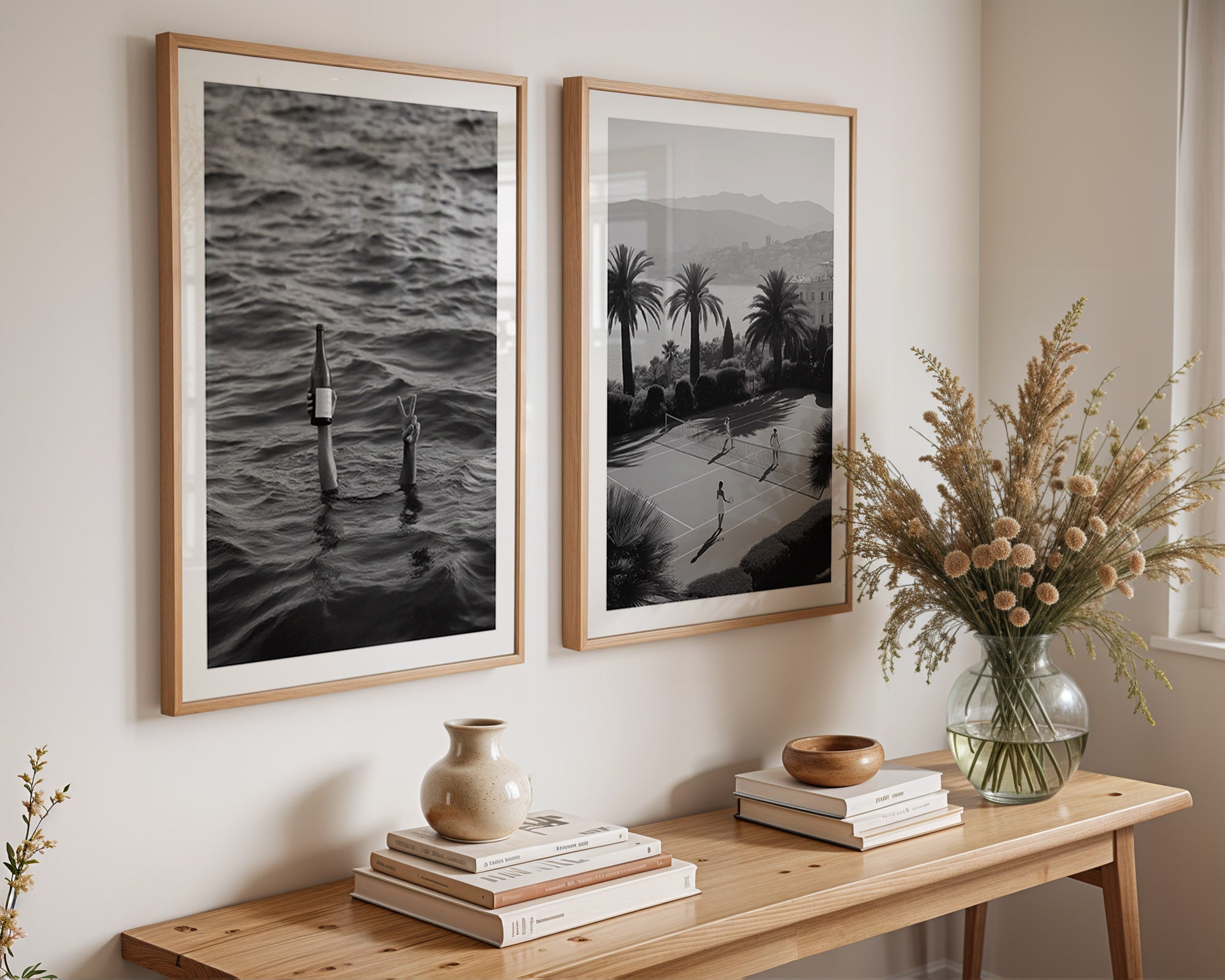 Two framed black and white artworks on a wall above a wooden console table with decorative items.