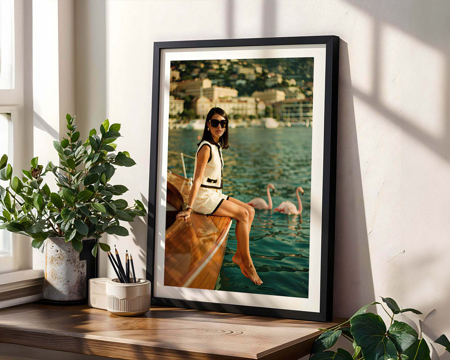 Framed photograph of a woman on a boat with swans in the background, placed on a wooden shelf.