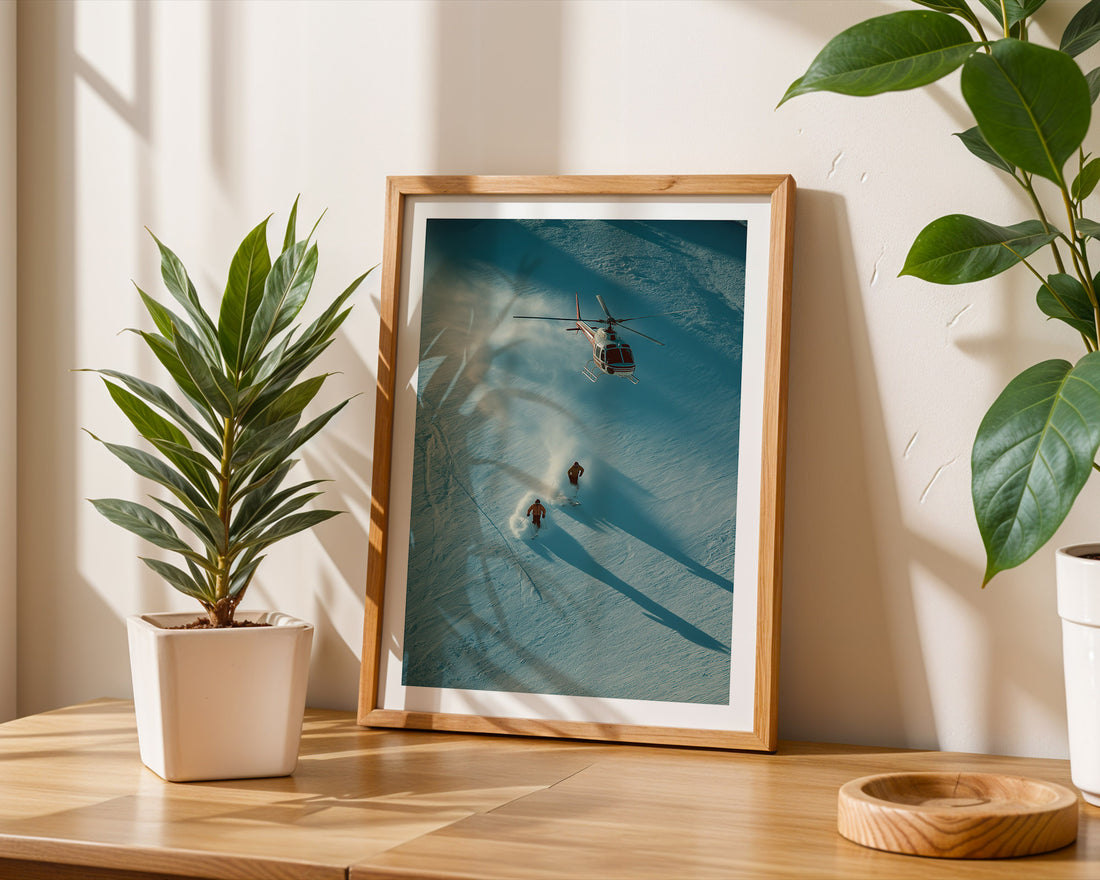 Framed photograph of a helicopter and people on a beach, placed on a wooden surface with plants around.