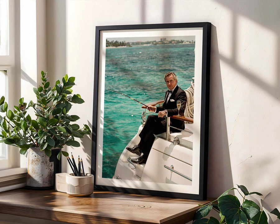 Framed picture of a man on a boat with a scenic background, placed on a wooden surface with plants.