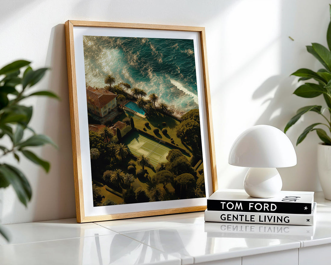 Framed artwork on a shelf with a white lamp and books in the background