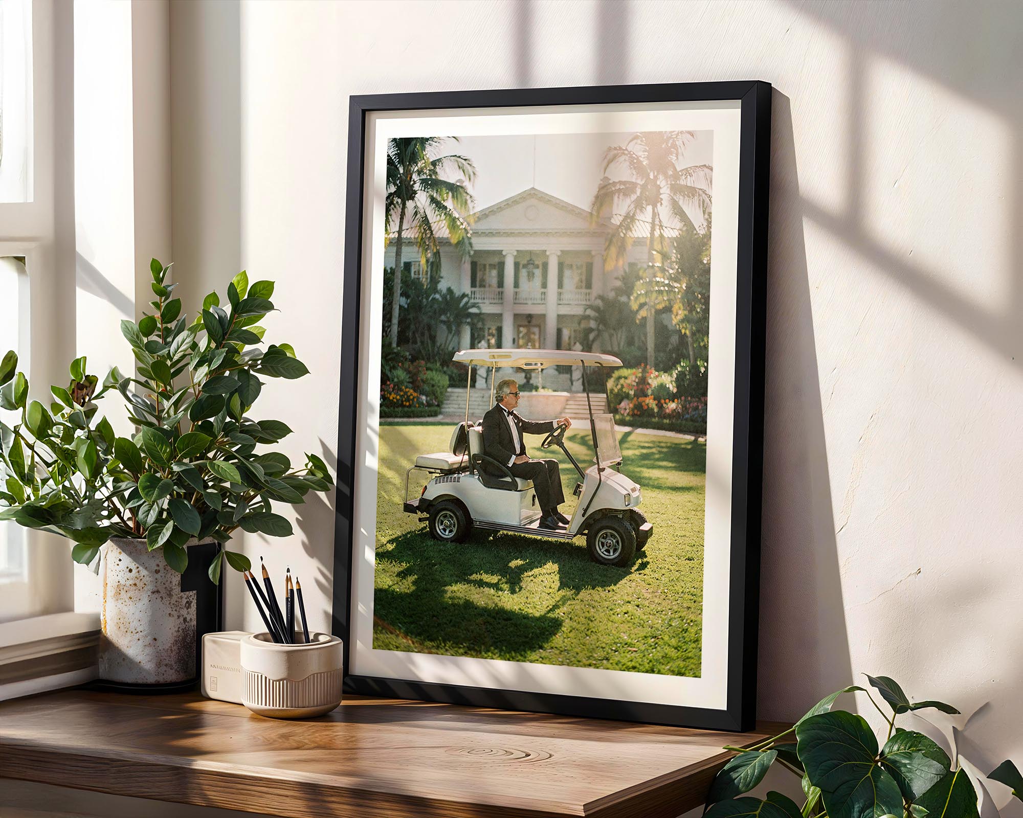Framed photograph of a man in a golf cart on a golf course, placed on a wooden shelf with plants.