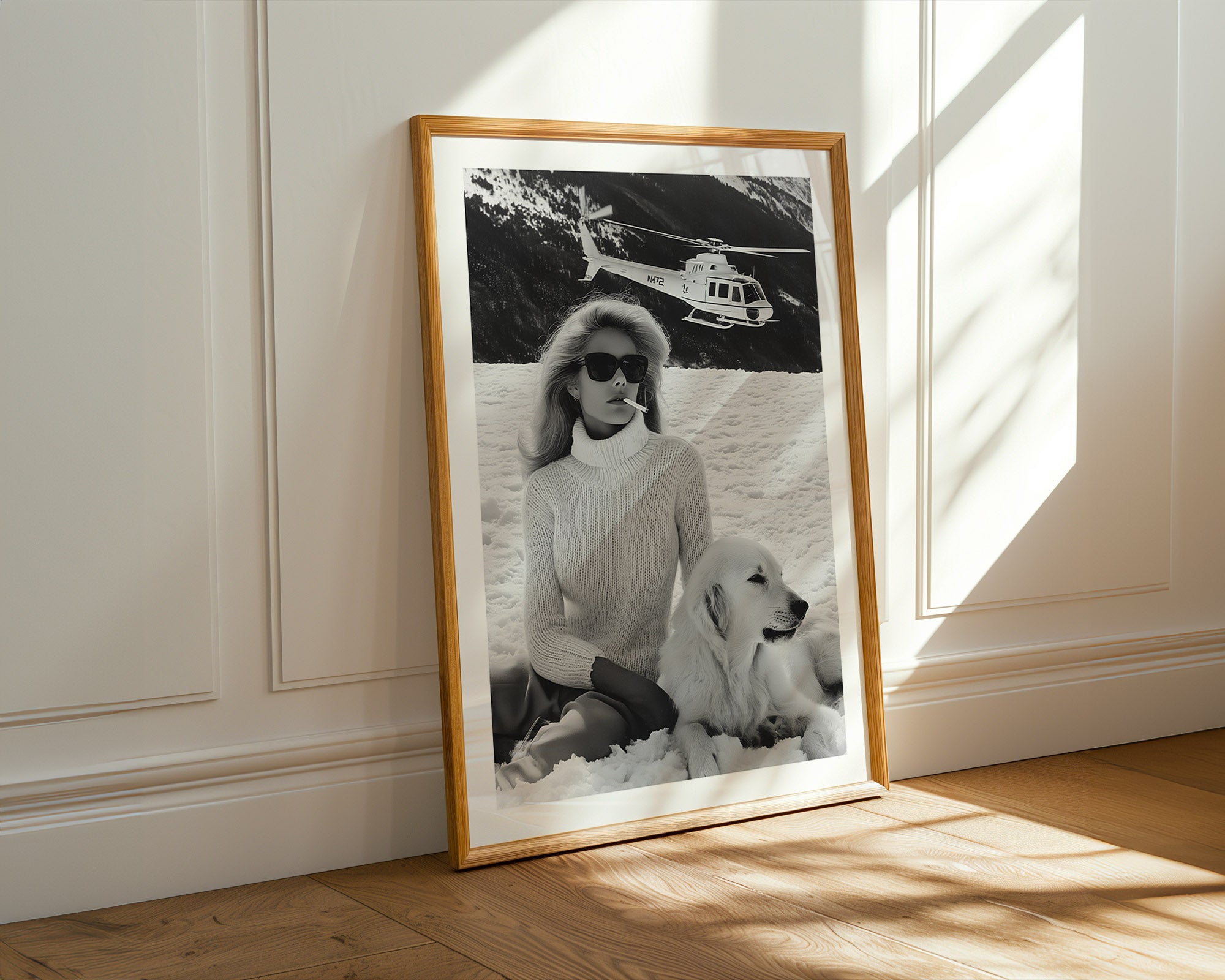 Framed black and white photograph of a woman with a dog on a beach, sunlight casting shadows on the wall.