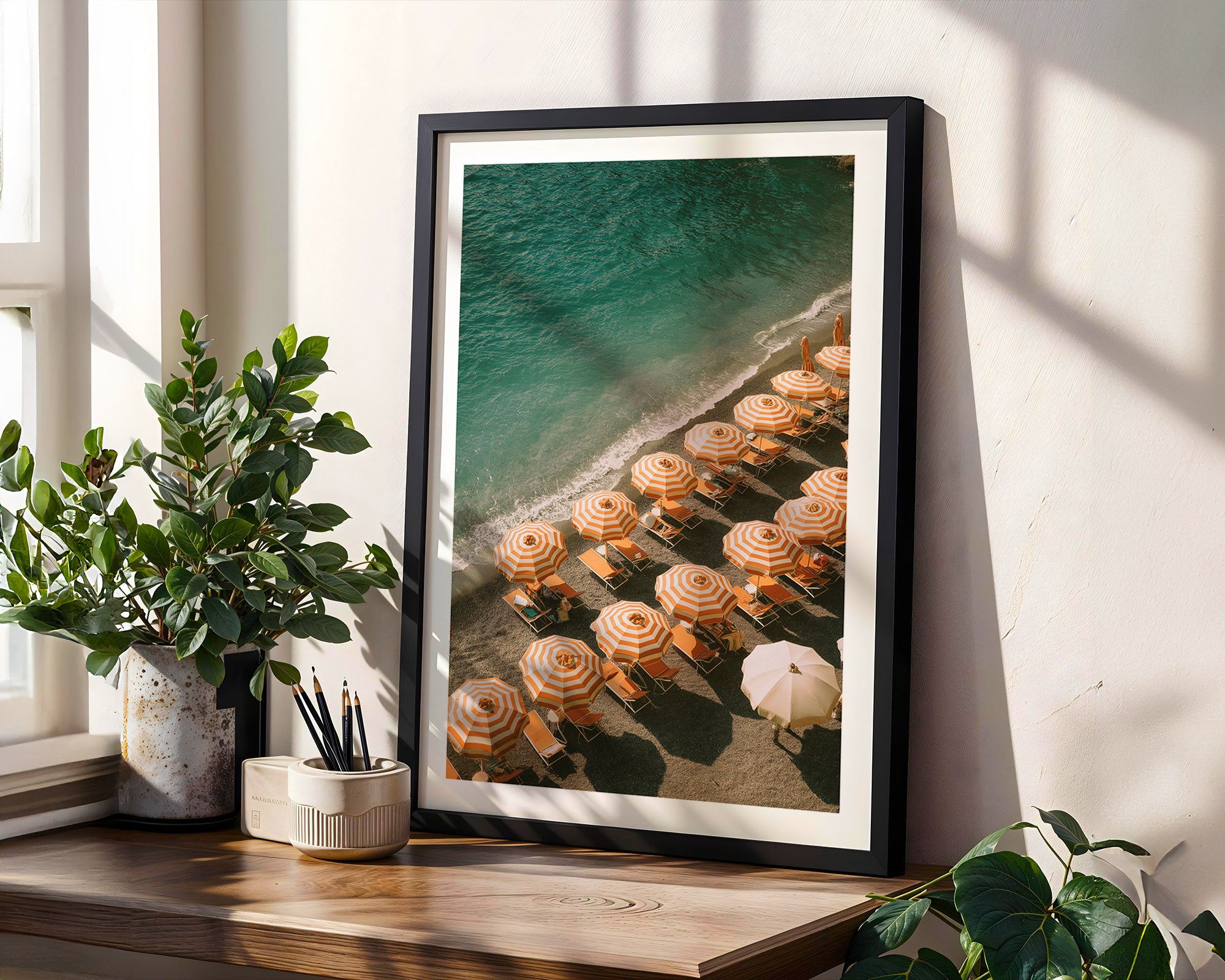Framed artwork of a beach scene with lounge chairs on a wooden shelf.