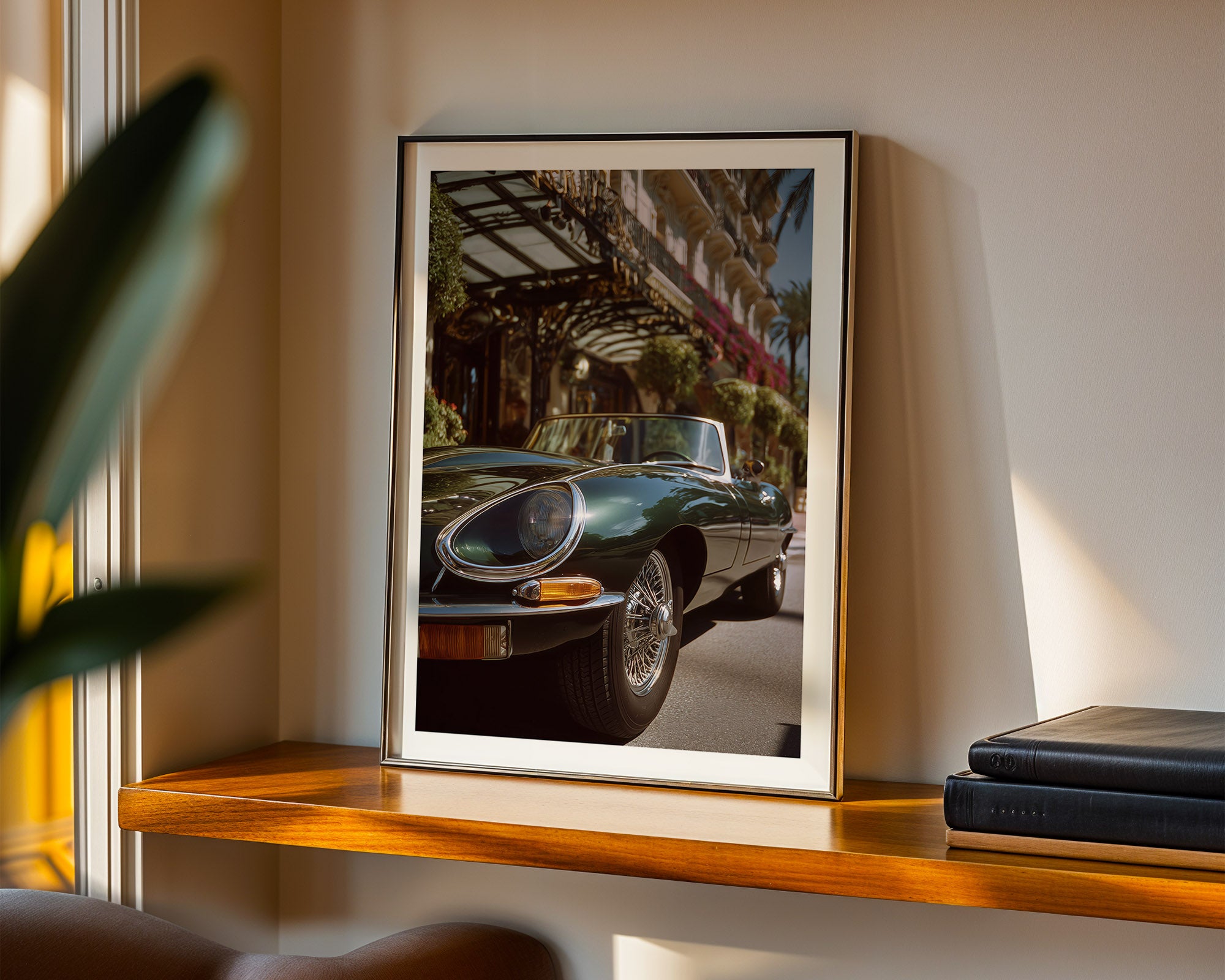 Framed photograph of a classic car on a wooden shelf with a plant and books in the background.