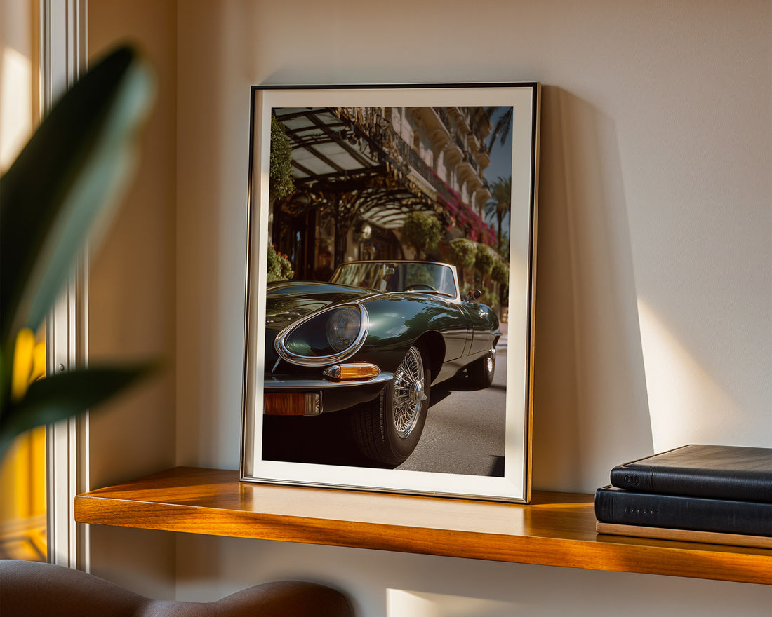 Framed photograph of a classic car on a wooden shelf with a plant and books in the background.