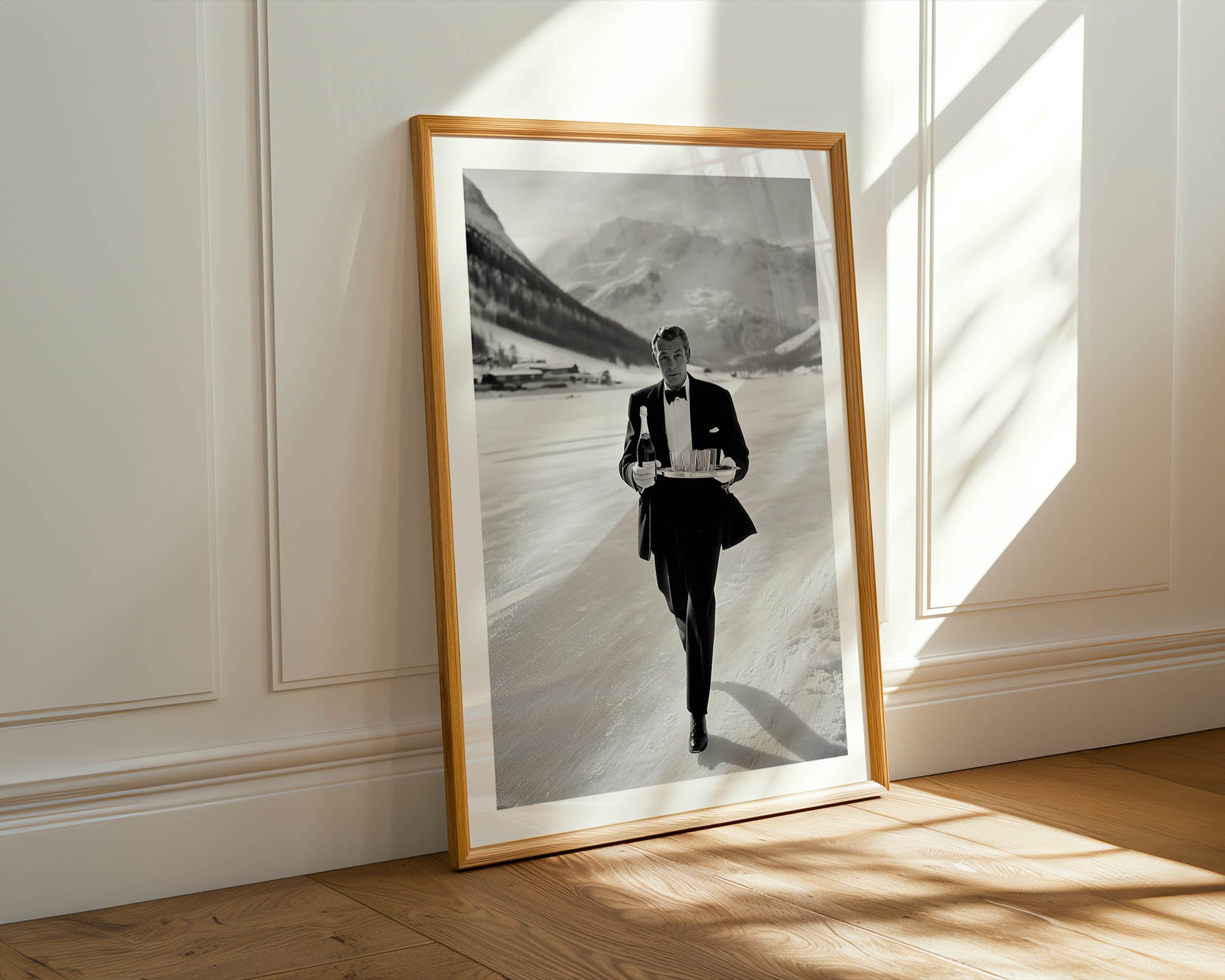 Framed black and white portrait of a man in a suit against a mountainous background, placed on a wooden floor with sunlight casting shadows.