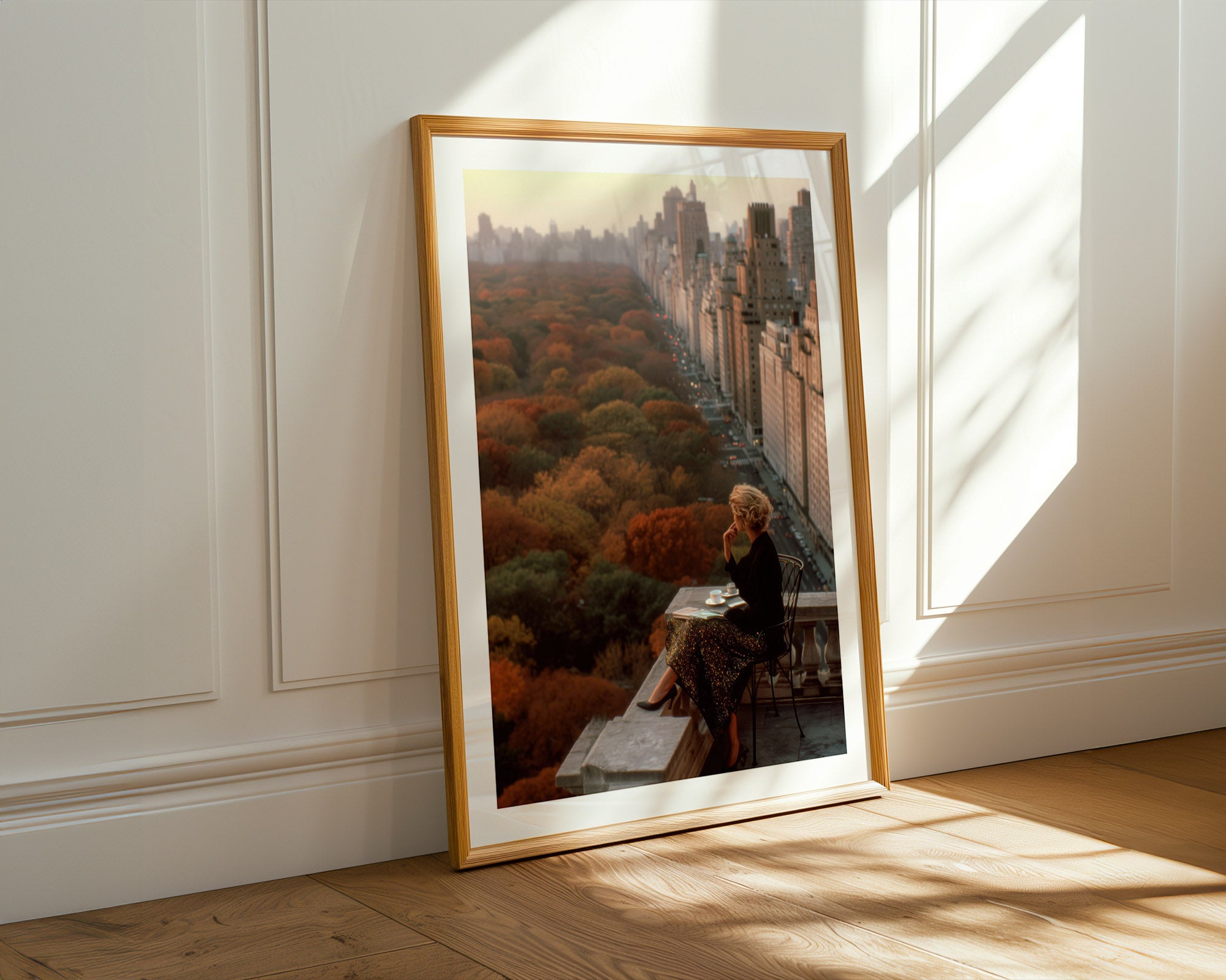 Framed artwork of a cityscape over Central Park NYC on a wall with sunlight streaming in.