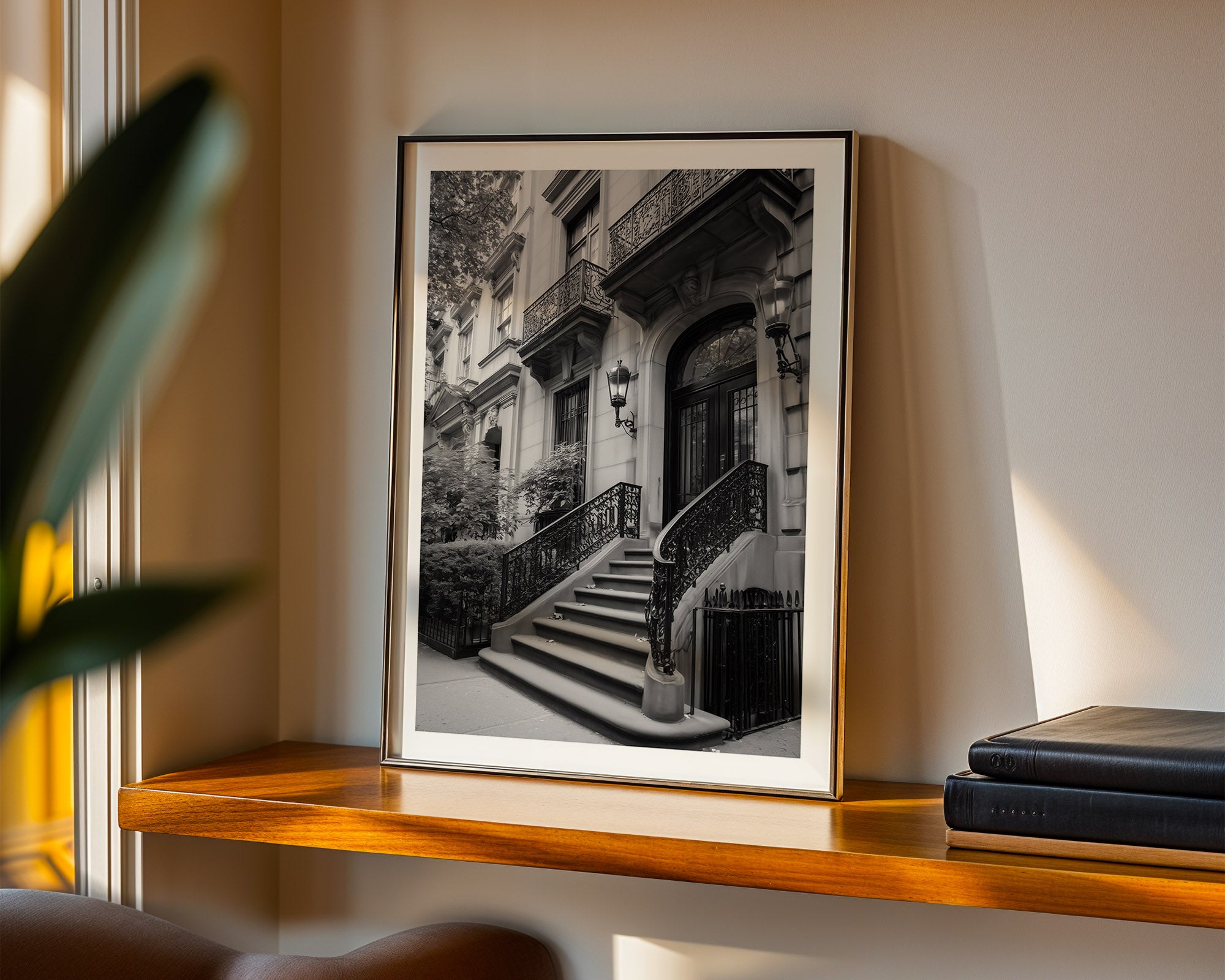 Framed black and white print of a staircase on upper eastside on a wooden shelf.