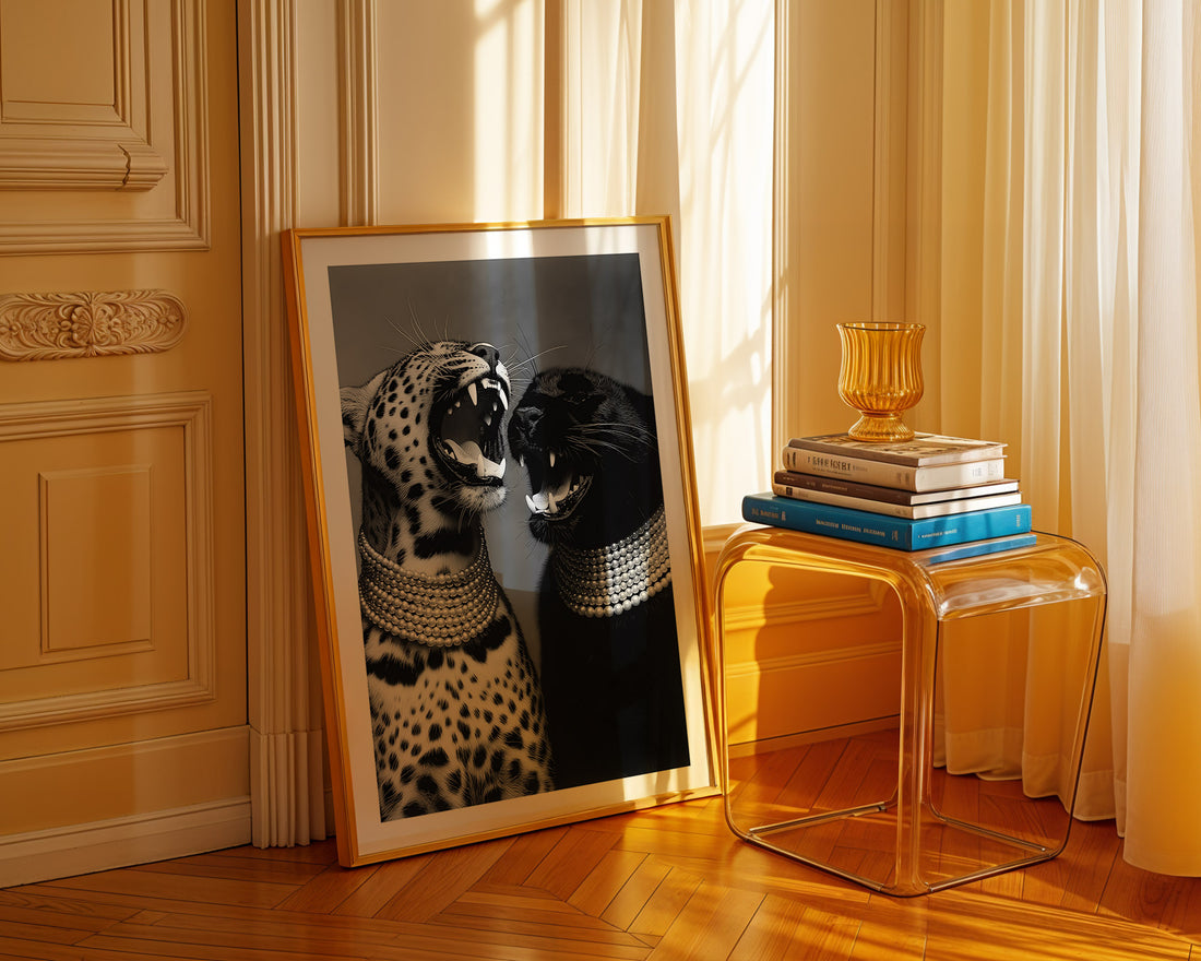 Framed artwork of a leopard and panther on a wooden floor with a clear side table and books in the background.