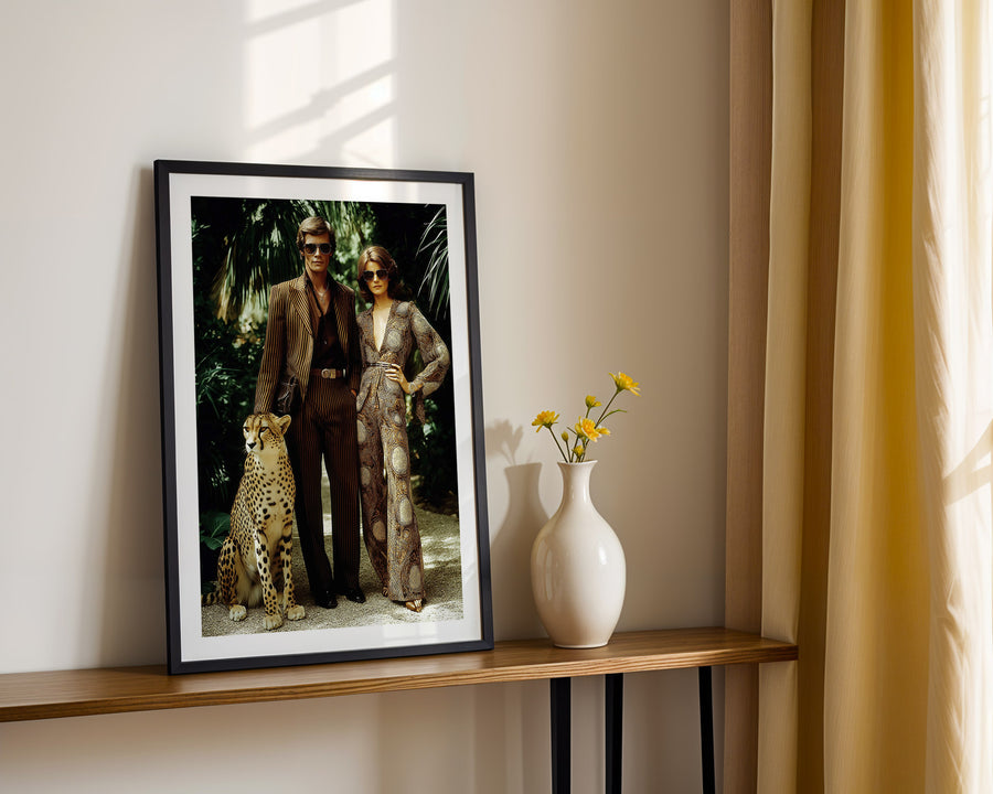 Framed artwork of a couple with a cheetah on a wooden shelf with a vase and flowers.