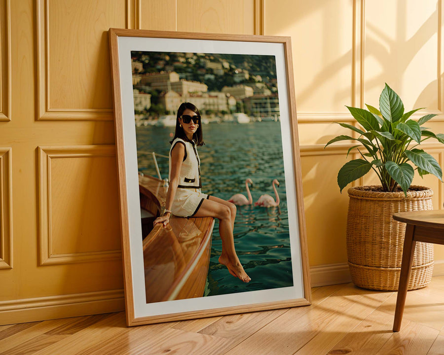 Framed photograph of a woman on a boat with swans, leaning against a wooden wall.