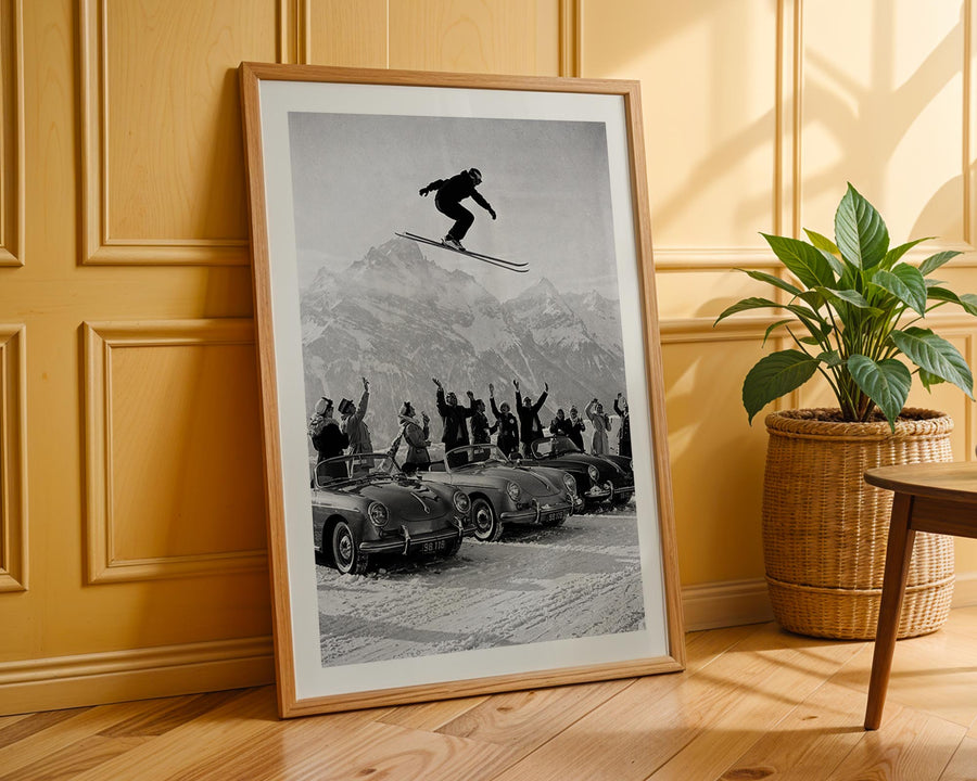 Framed black and white print of a skier in action with people watching, on a wooden floor.