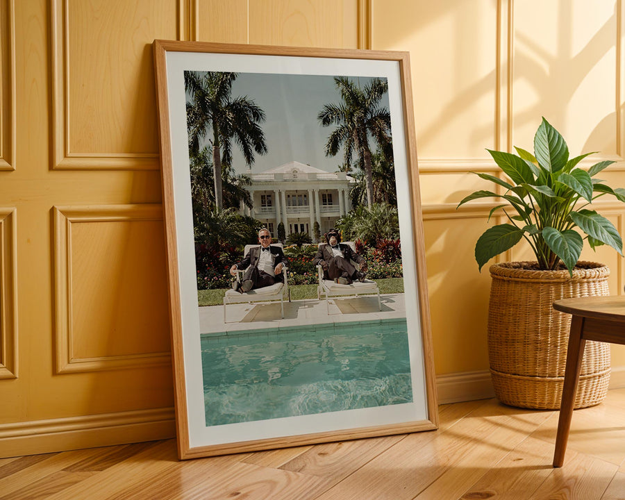 Framed photograph of a pool scene with people sitting by a pool, leaning against a wooden wall.