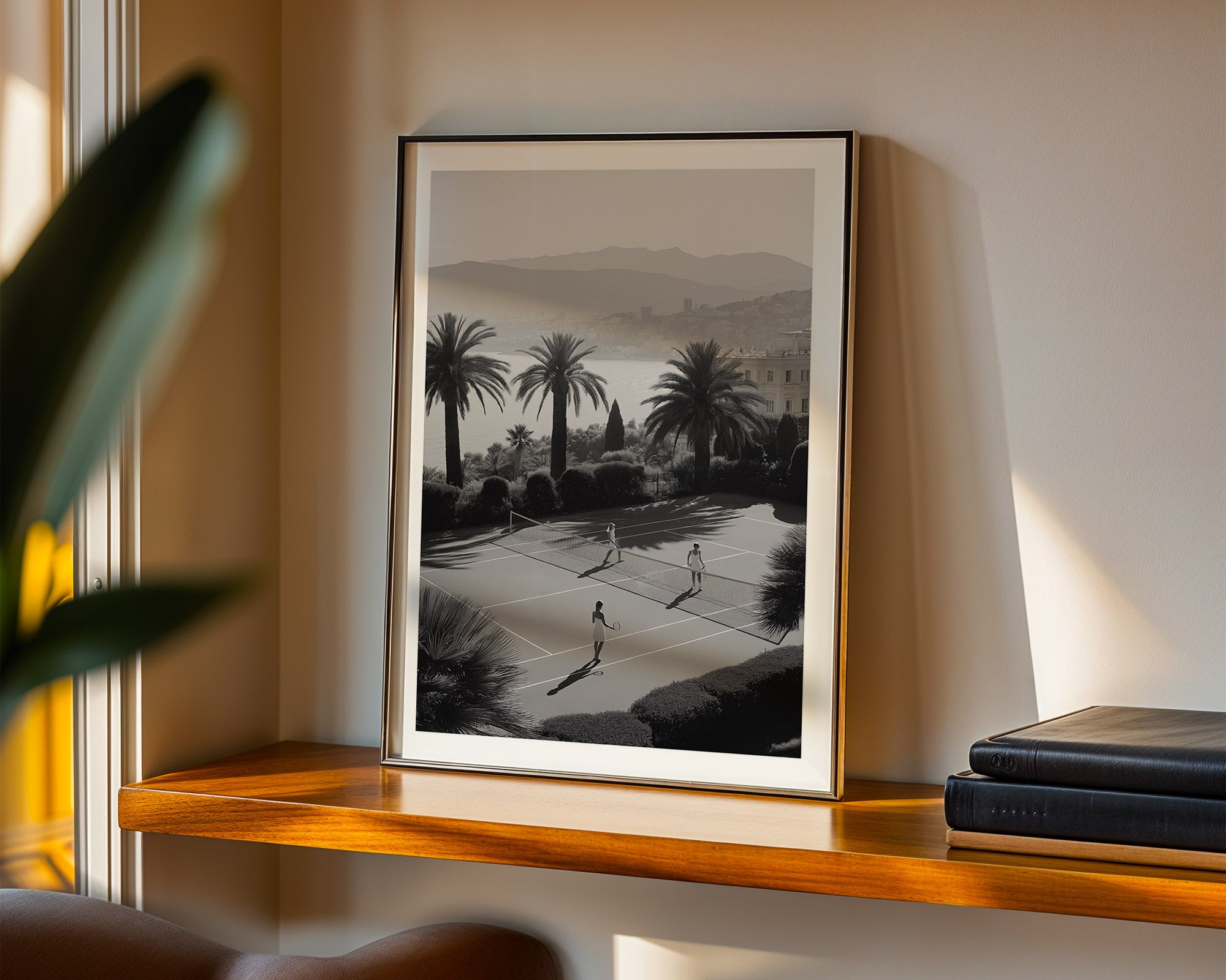 Framed artwork of a scenic landscape with palm trees on a wooden shelf.