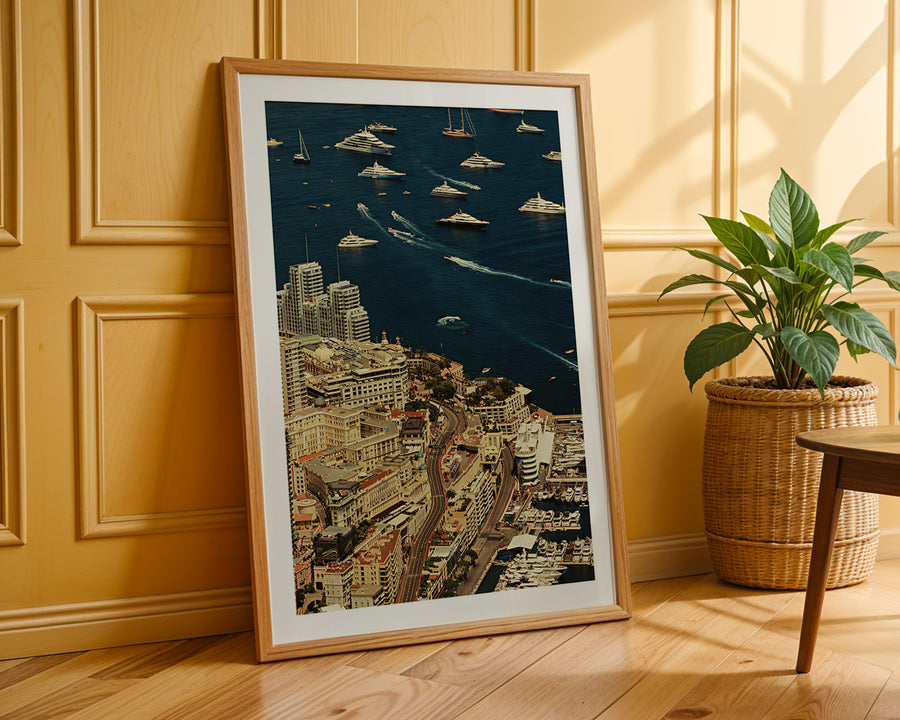 Framed cityscape artwork on a wooden floor with a plant in the background
