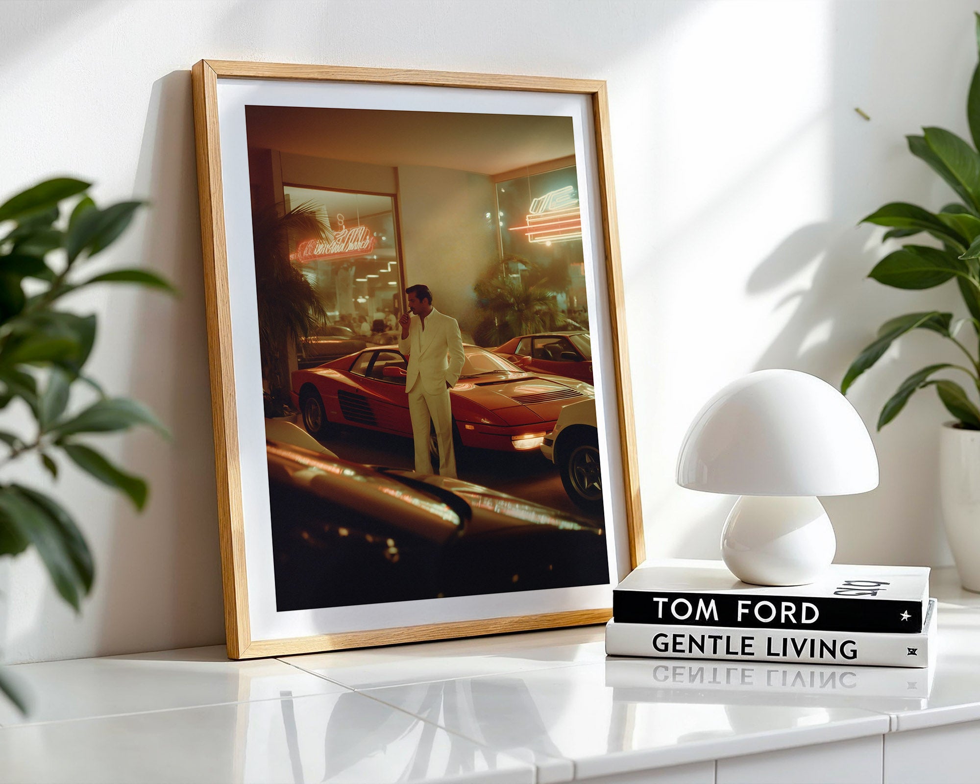 Framed photograph of a man in a car showroom with a white lamp and 'Tom Ford Gentle Living' book on a shelf.