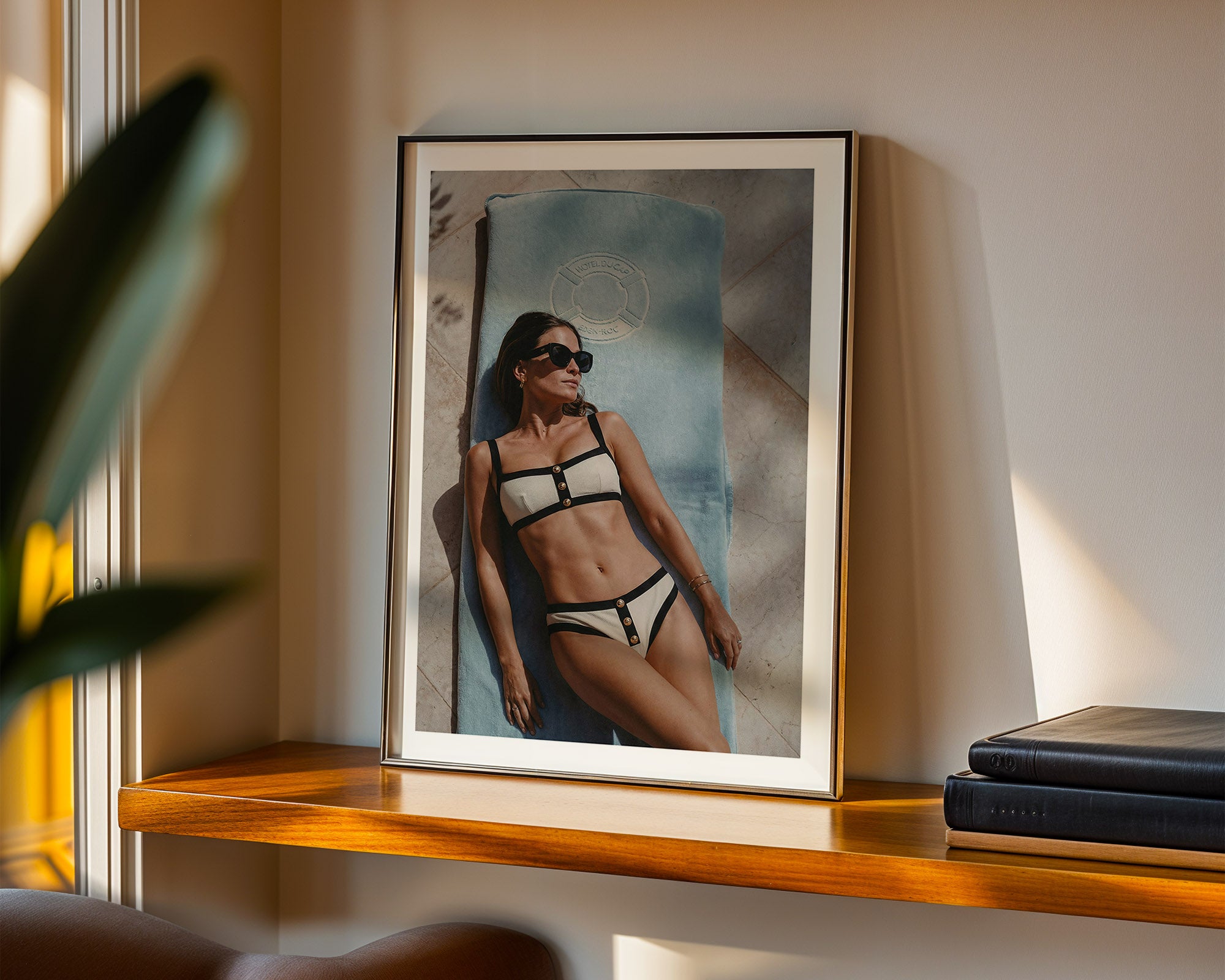 Framed photograph of a person in a Chanel bikini on a wooden shelf.
