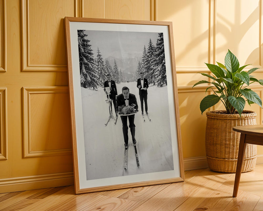 Framed black and white photograph of people skiing in a snowy landscape on a wooden wall.