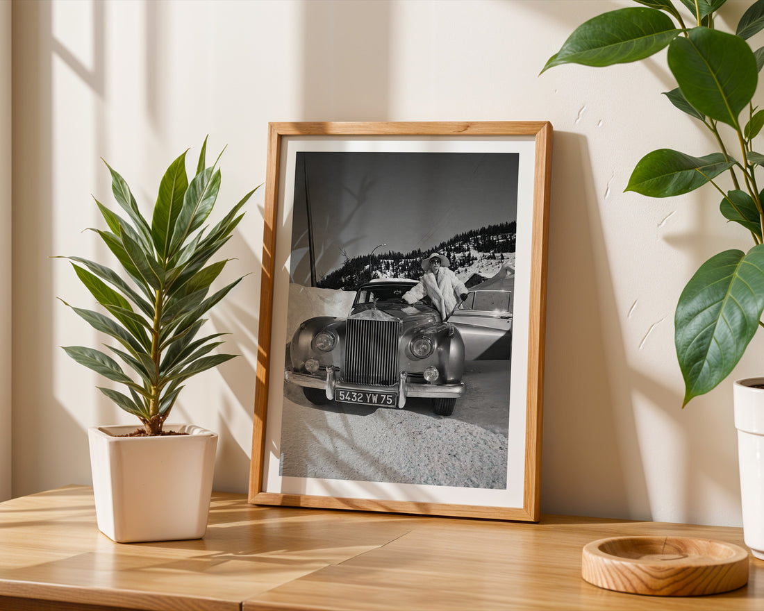 Framed black and white photo of a vintage Rolls-Royce on a wooden surface with plants.