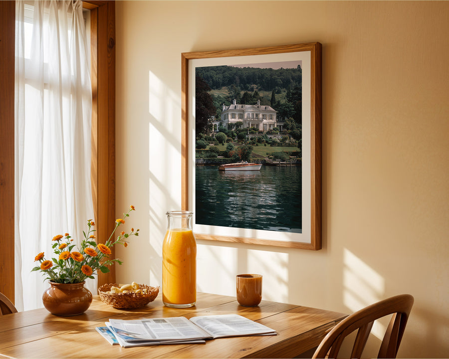 Dining room with a table set for breakfast, including a vase of flowers, a bottle of orange juice, and a newspaper. A framed picture of a house by a lake is on the wall.