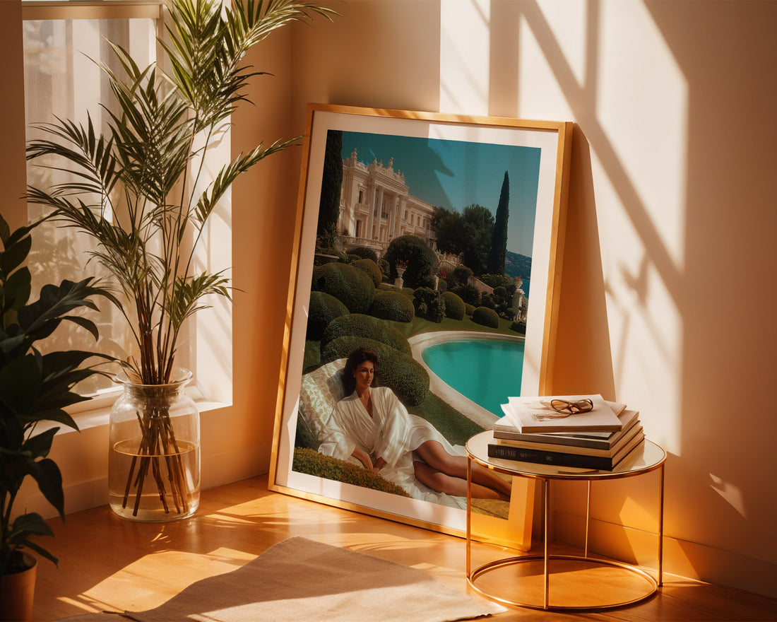 Framed artwork of a woman by a pool in a room with plants and a side table.
