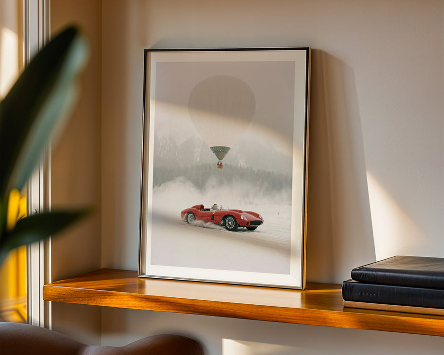 Framed artwork of a red car on a shelf with a plant and books in the background