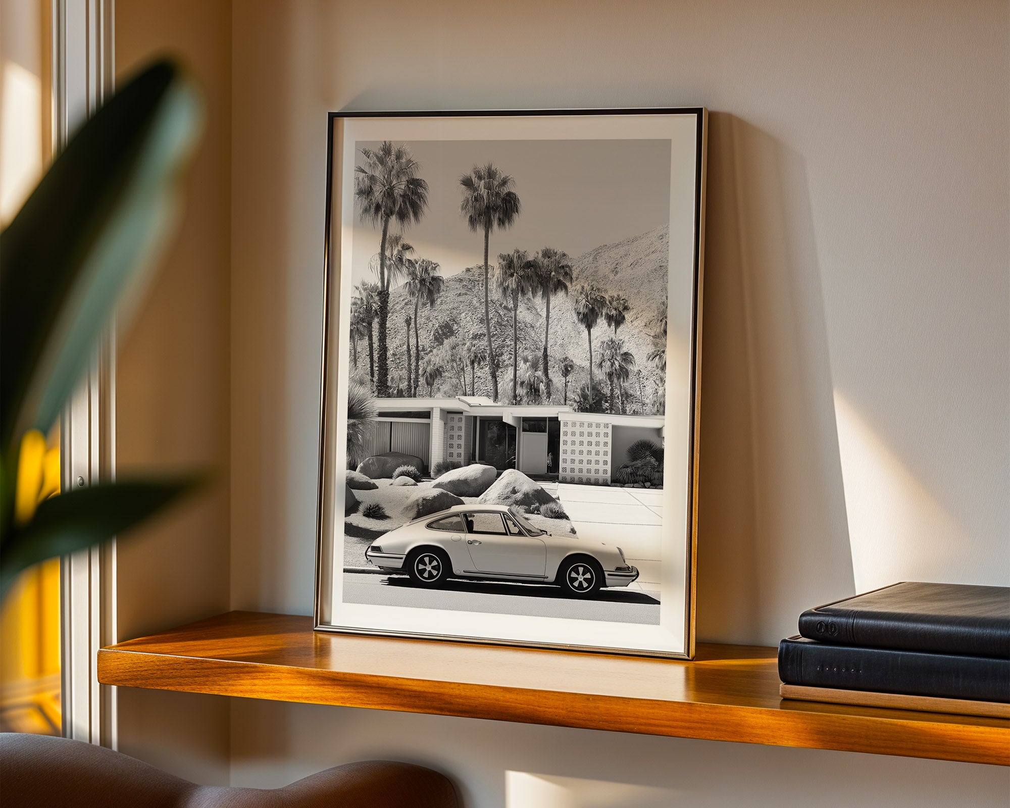 Framed black and white print of a car and palm trees on a shelf.