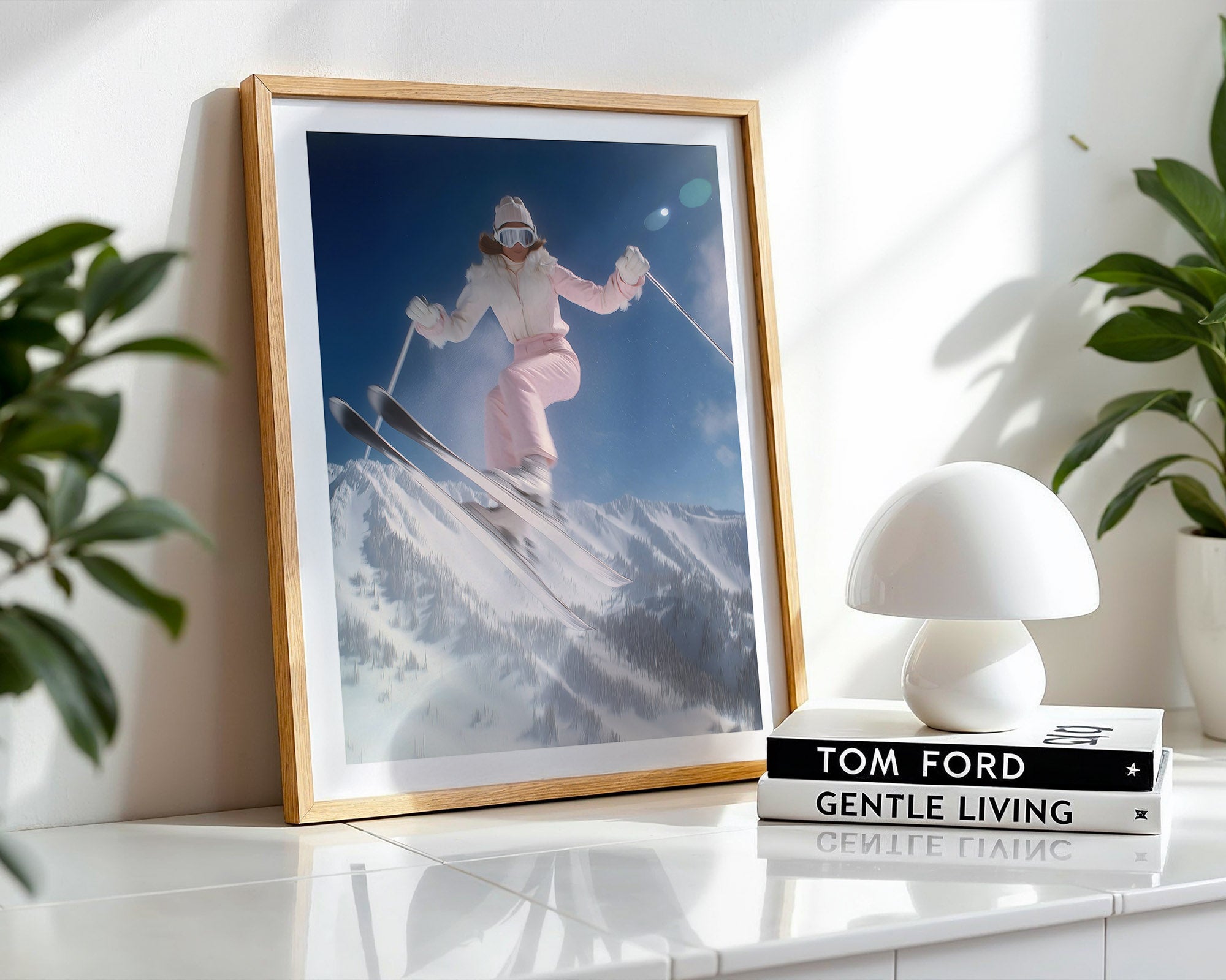 Framed photograph of a skier on a mountain with a white lamp and books on a shelf.
